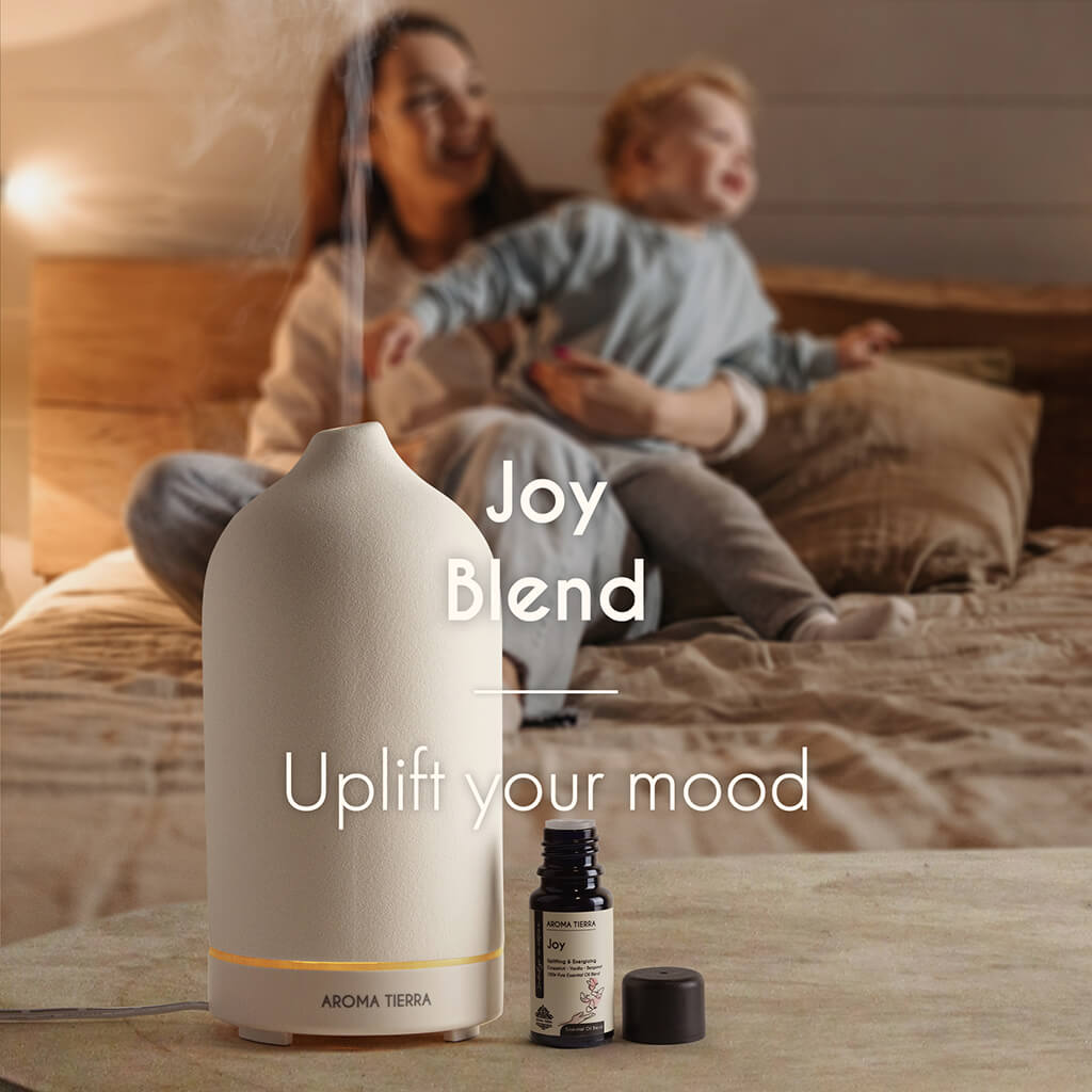 Aroma Tierra Joy Essential Oil Blend diffusing in a cozy room as mother plays with her child