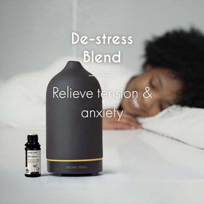 Woman resting in a calm bedroom with diffuser and Aroma Tierra De-stress Blend for anxiety relief