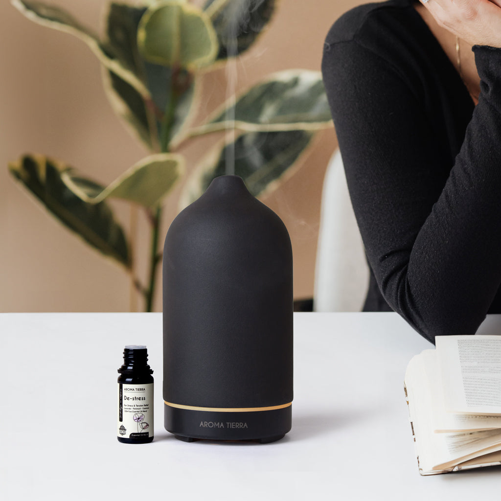 Lady using de-stress essential oil blend by Aroma Tierra in diffuser at her work desk